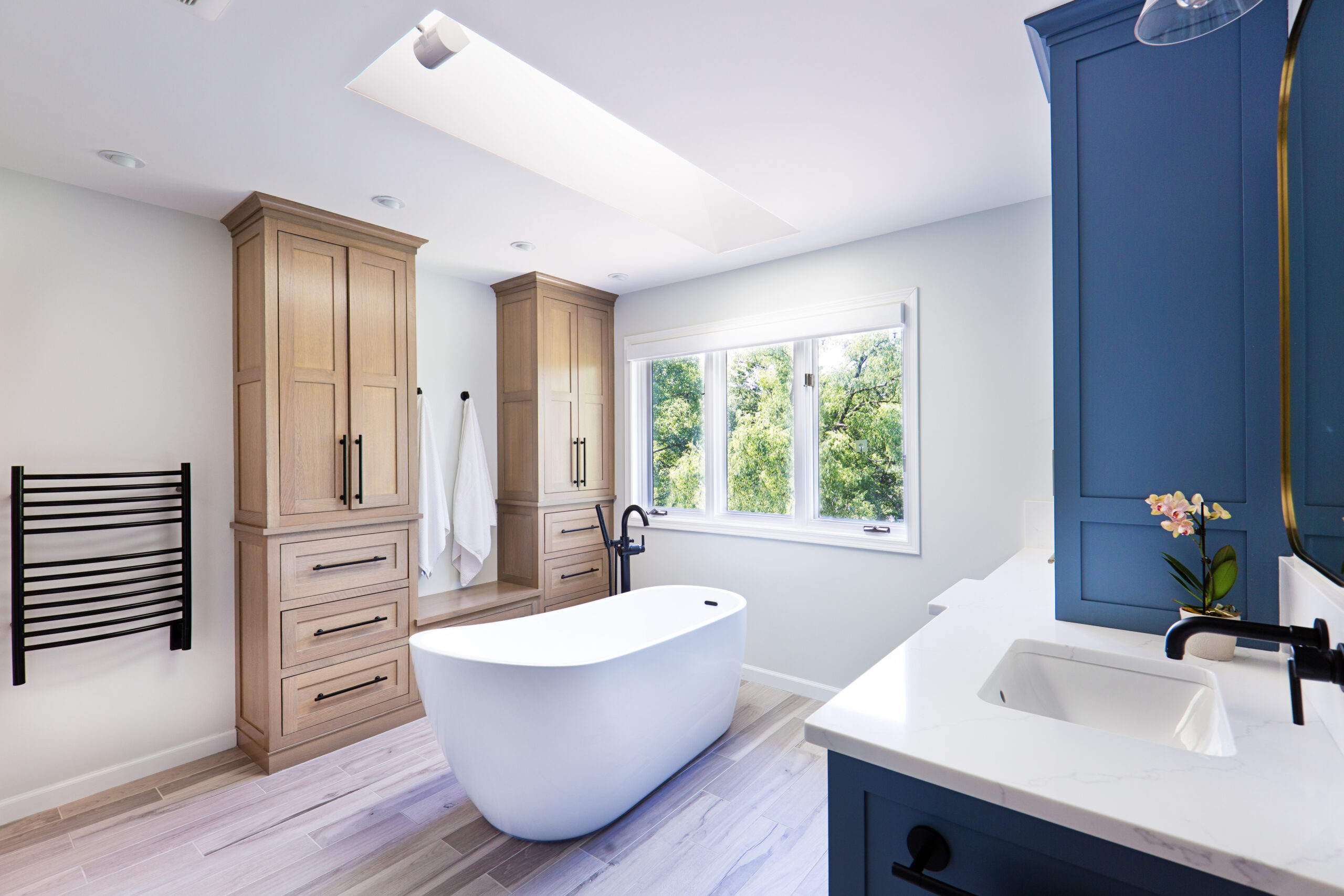 A contemporary modern bathroom design. featuring a contemporary classic freestanding cast iron bathtub against a scenic window.