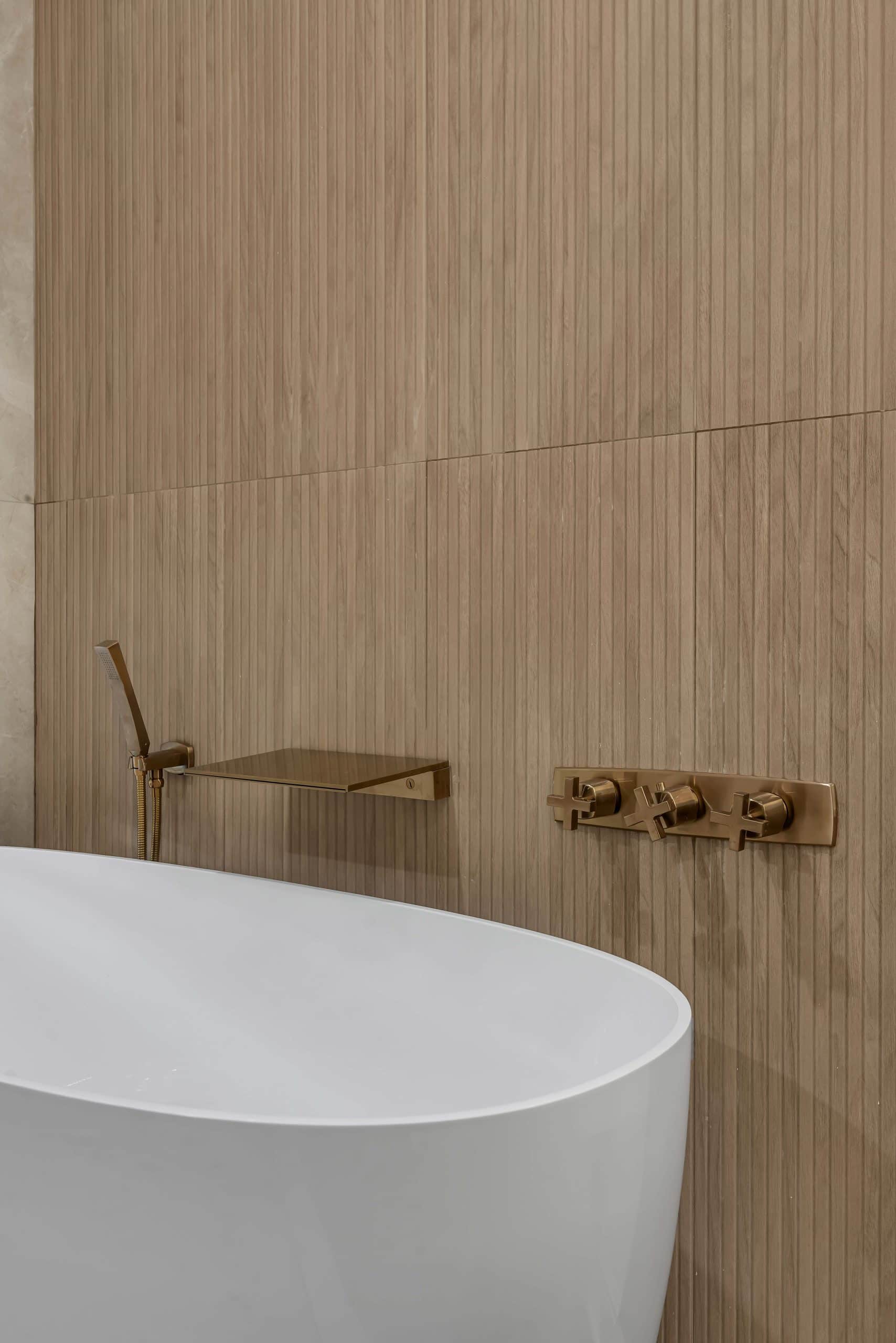 Pleasanton master bathroom — brushed-gold wall-mount tub filler with waterfall spout and cross handles on fluted oak