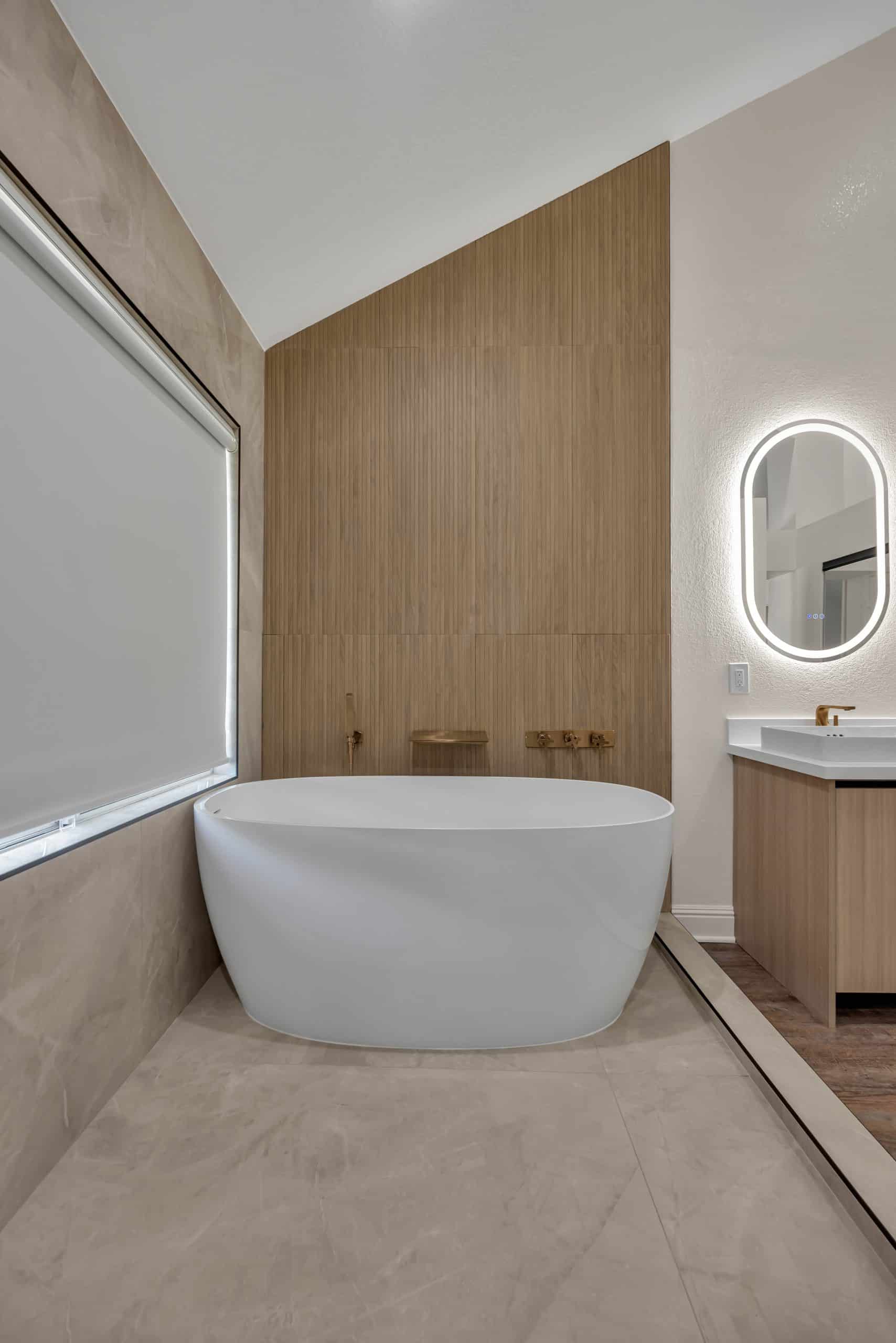 Pleasanton master bathroom — freestanding soaking tub against a fluted white-oak wall with a brushed-gold tub filler