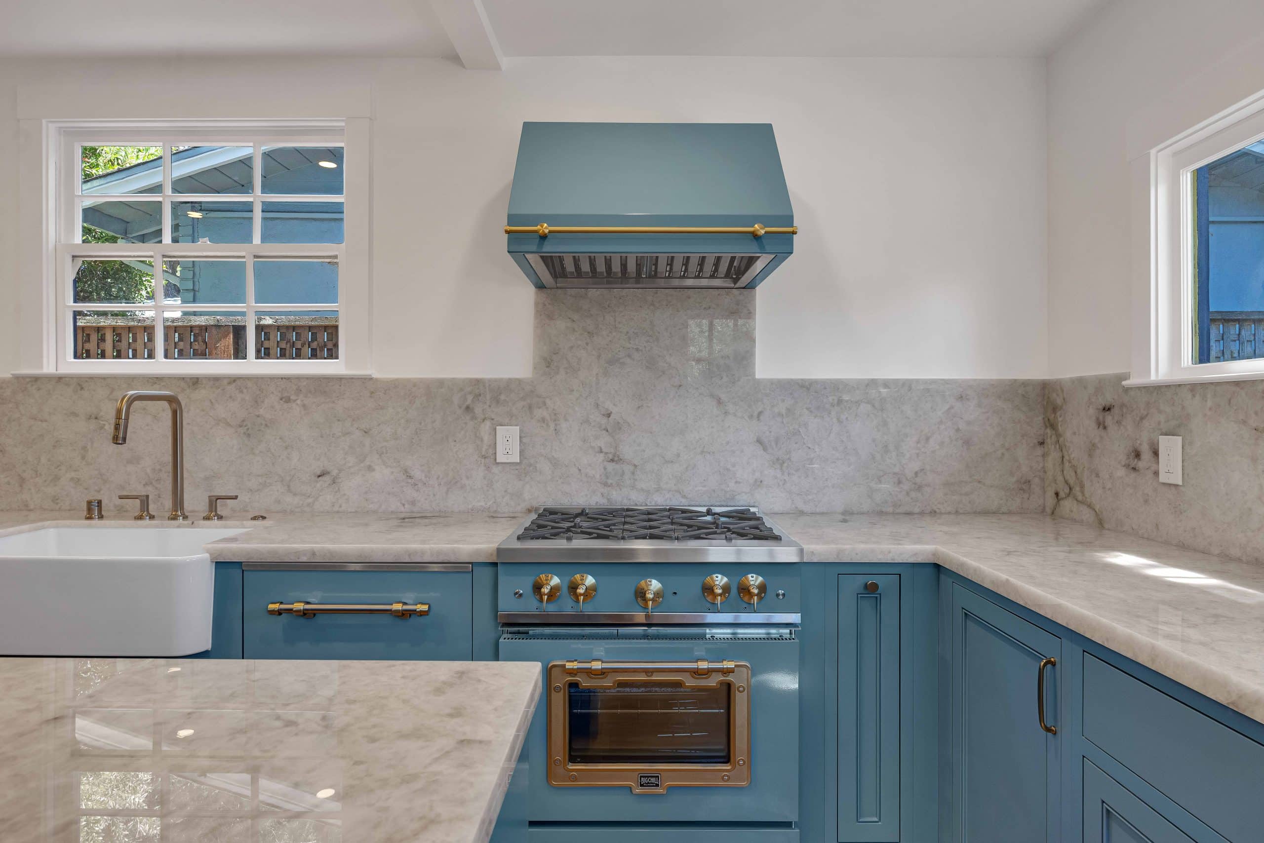 Menlo Park kitchen — teal vintage-style range and matching hood with brass trim against a marble backsplash