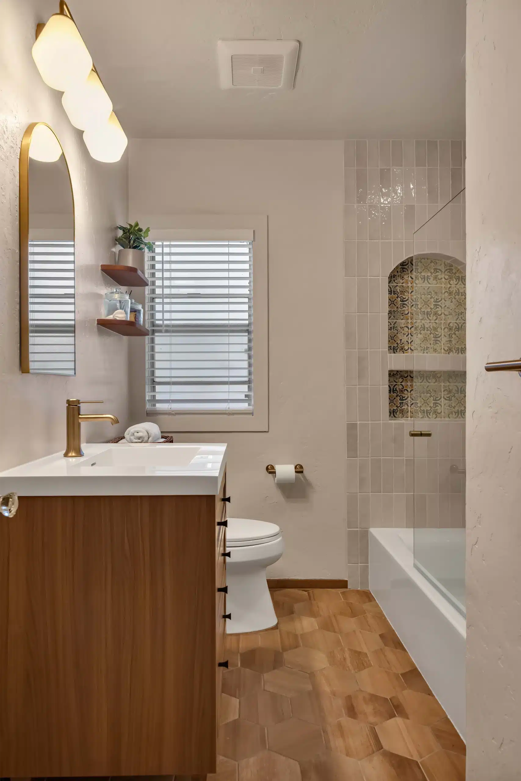 Finished Burlingame bathroom showing the oak vanity, tub-shower and wood-look flooring