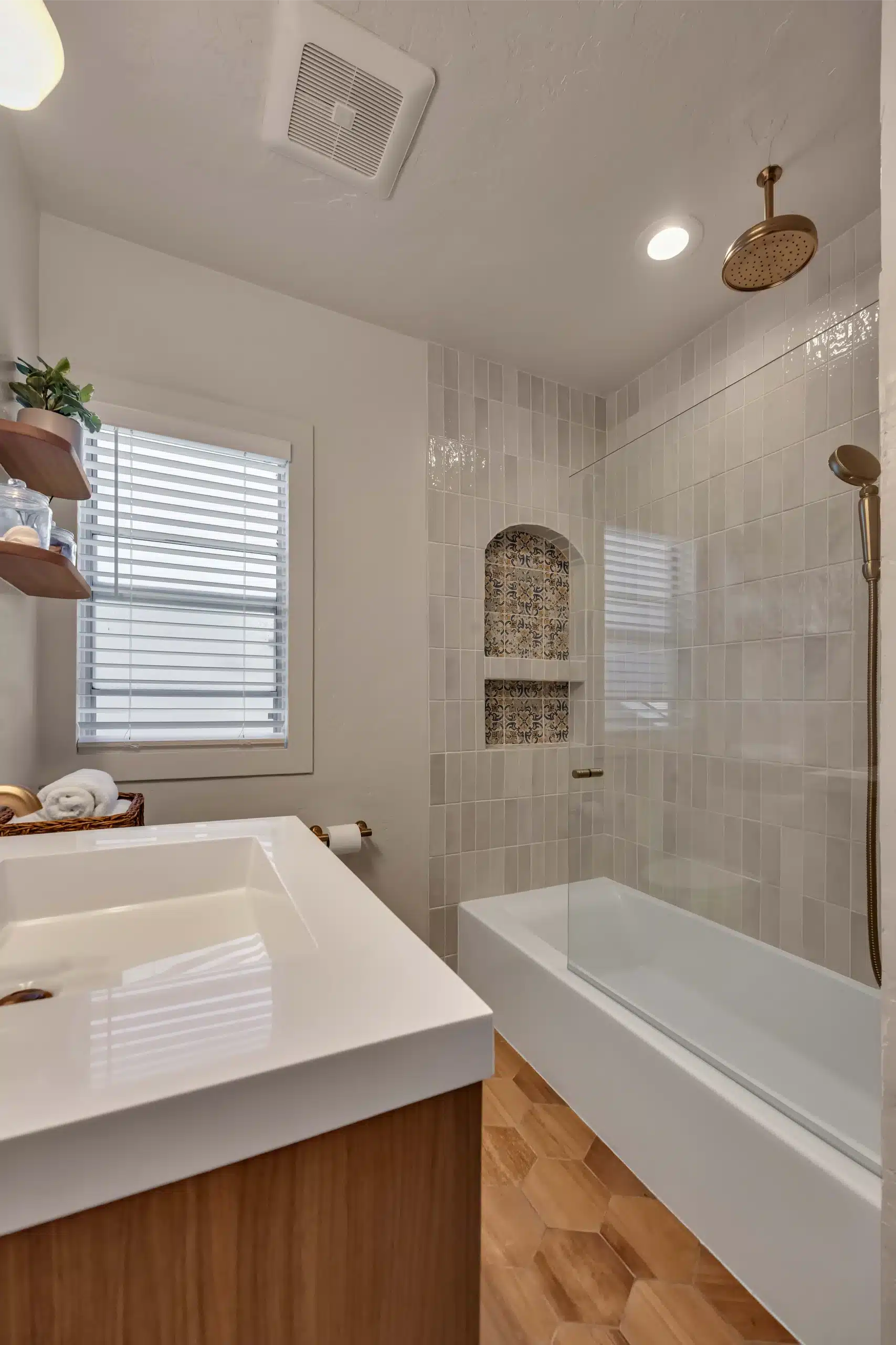 Bathroom with tub under the window and a brass shower fitted to the surround