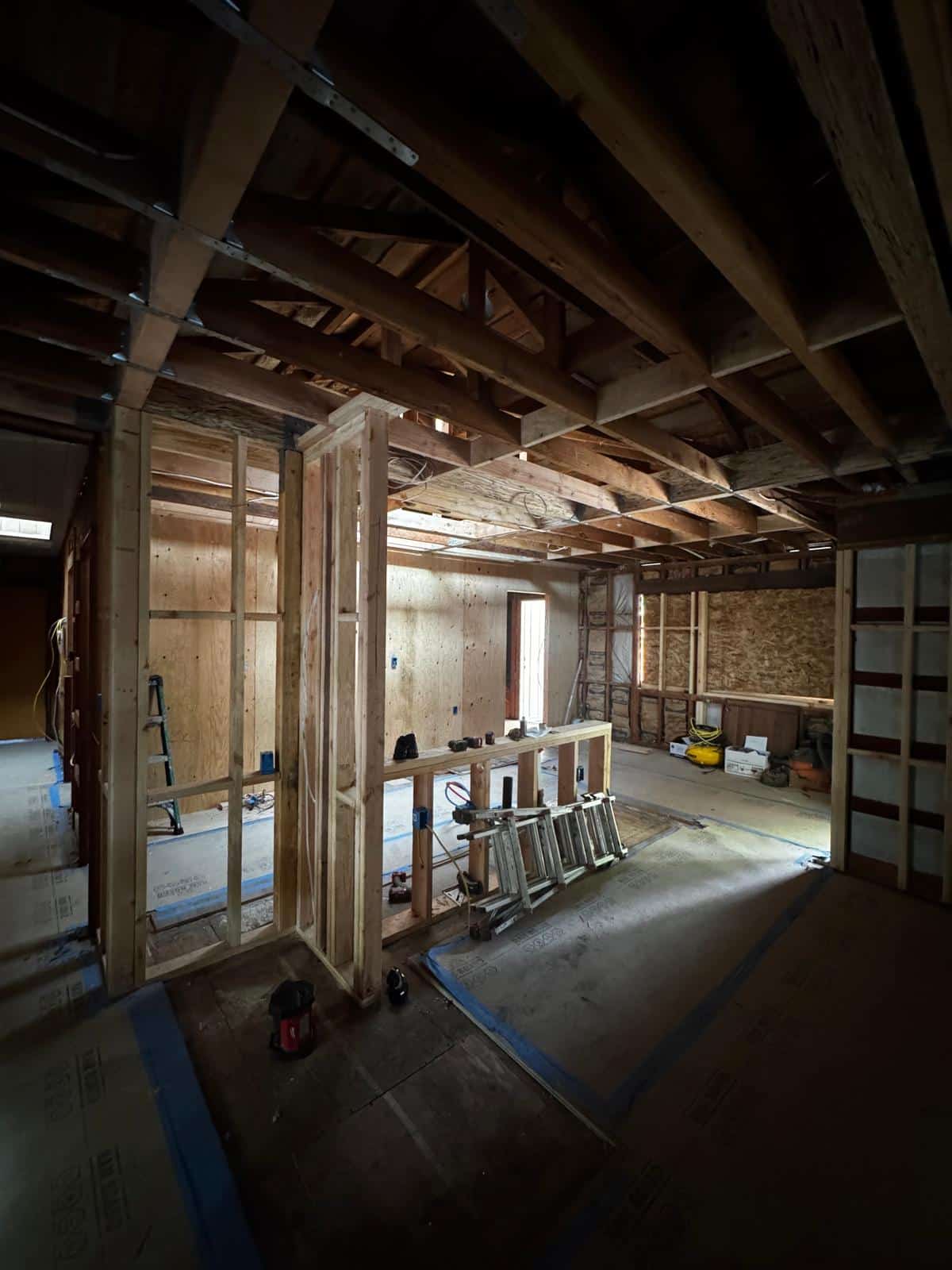 New stud framing and plywood shear panels with ceiling joists and roof trusses exposed
