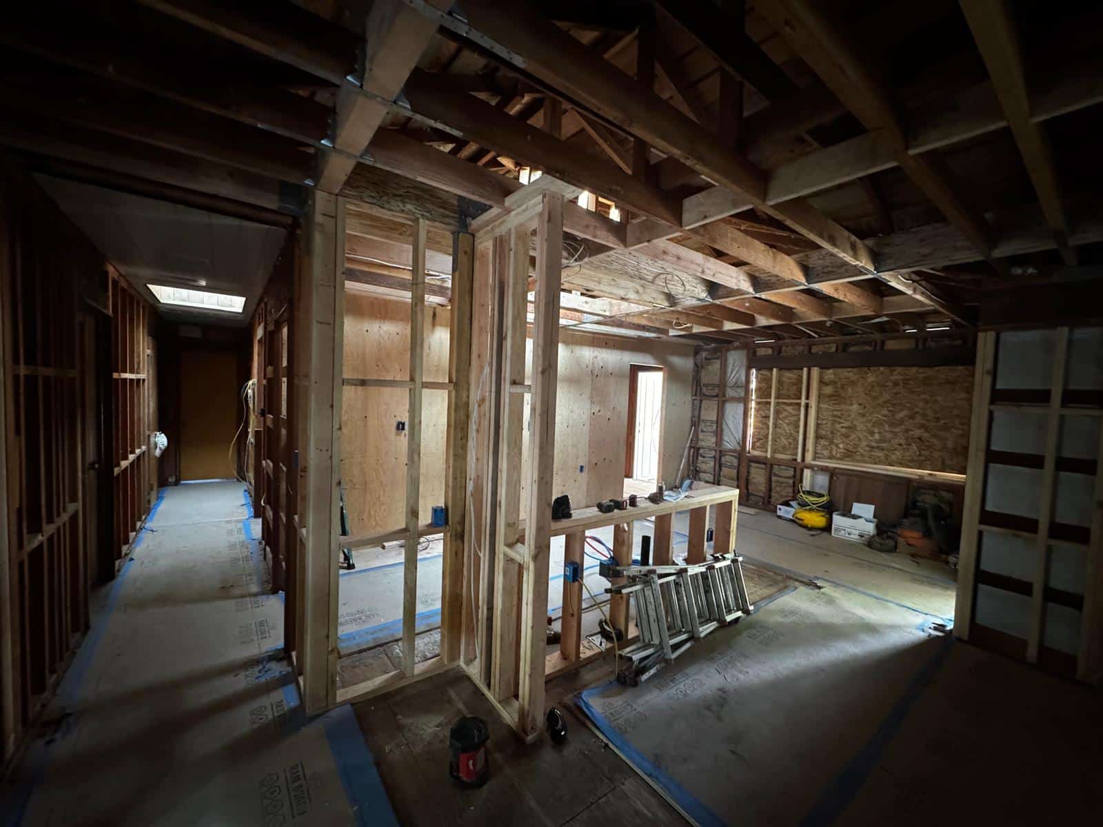 Framed rooms and hallway with floor protection in place during a full house remodel