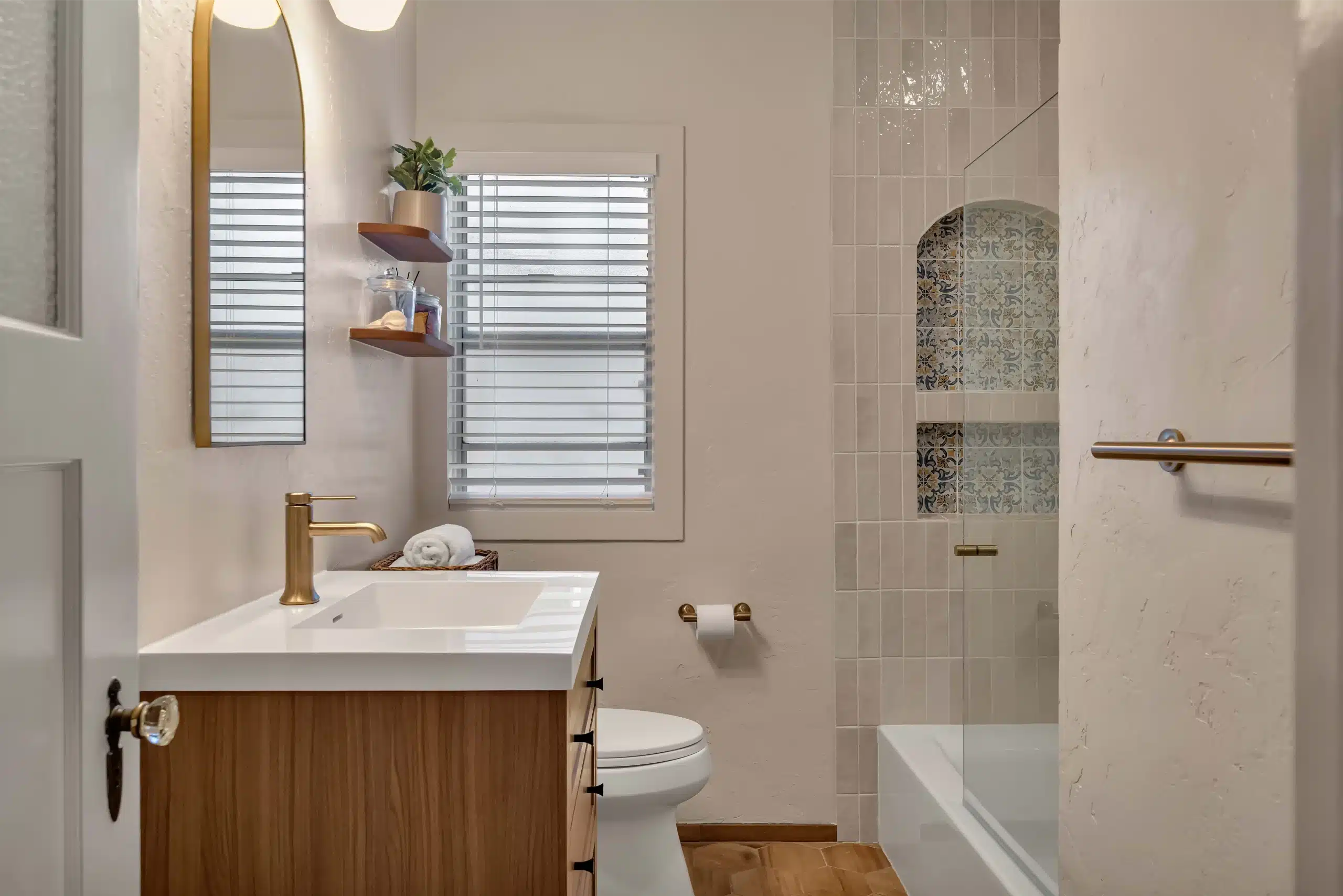 Completed bathroom remodel in Burlingame with a floating wood vanity, arched tiled niche and brass fixtures